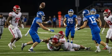 Football player fumbles, crucial turnover in NFL game action.