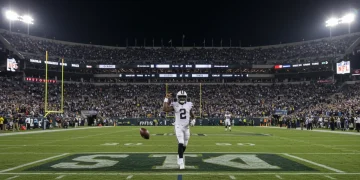 Quarterback celebrating game-winning touchdown in a packed NFL stadium at night