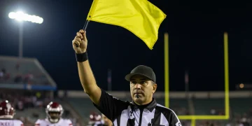 NFL referee throwing a yellow flag during a highly contested game, symbolizing controversial calls.