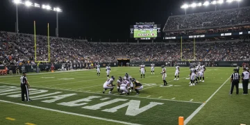 NFL stadium at night with players huddled during a crucial fourth-quarter game.