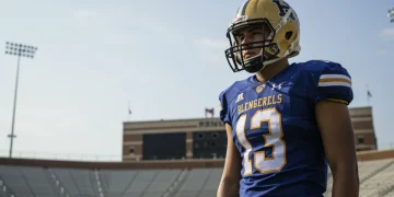 High school football player looking at college stadium with determination